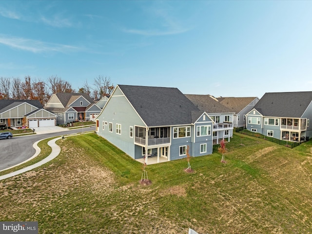 back of house with a lawn and a sunroom