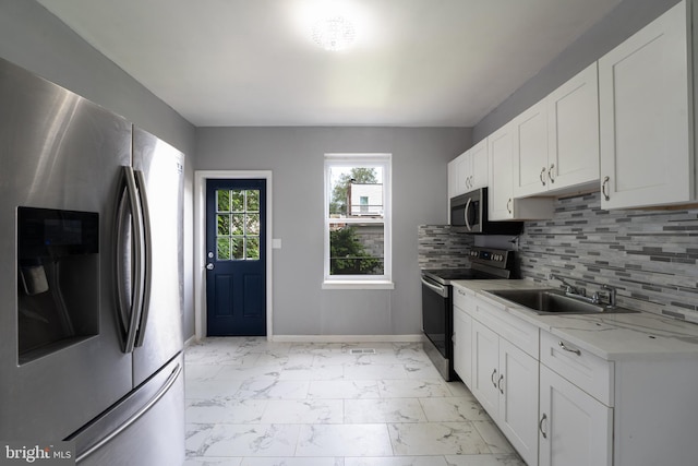 kitchen featuring stainless steel appliances, white cabinetry, sink, tasteful backsplash, and light stone countertops