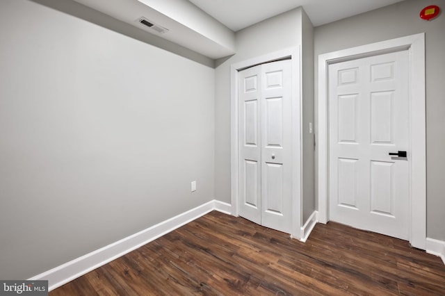 unfurnished bedroom with dark hardwood / wood-style floors and a closet