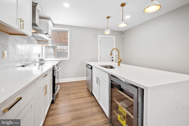 kitchen featuring light hardwood / wood-style floors, beverage cooler, sink, appliances with stainless steel finishes, and decorative light fixtures