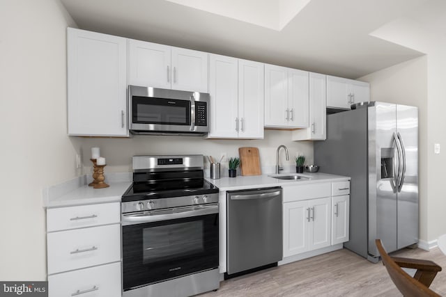 kitchen with white cabinets, stainless steel appliances, light hardwood / wood-style flooring, and sink