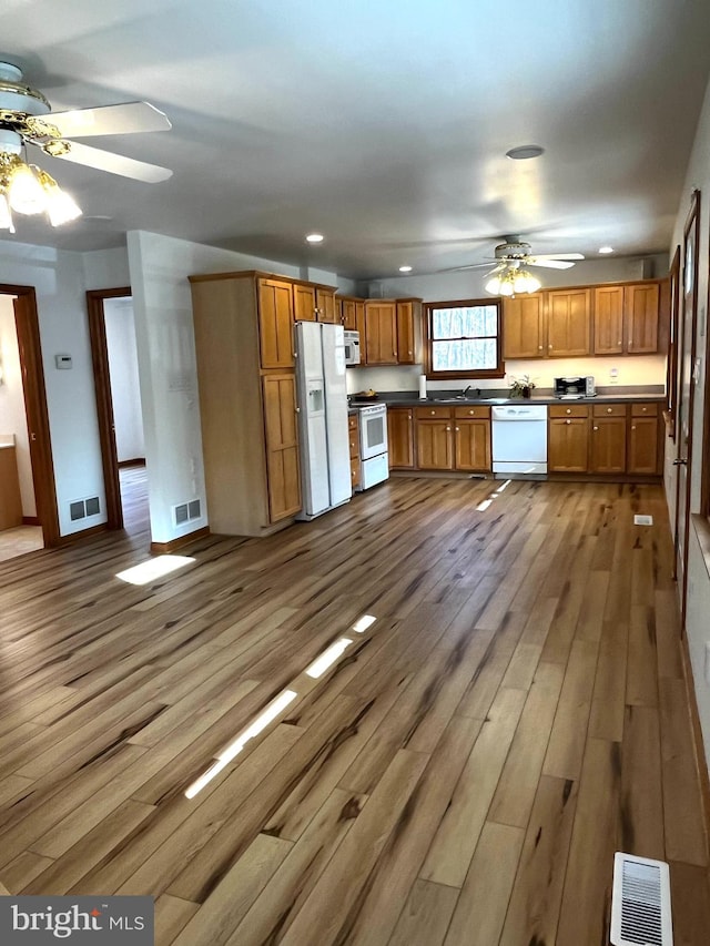 kitchen featuring hardwood / wood-style floors, ceiling fan, white appliances, and sink