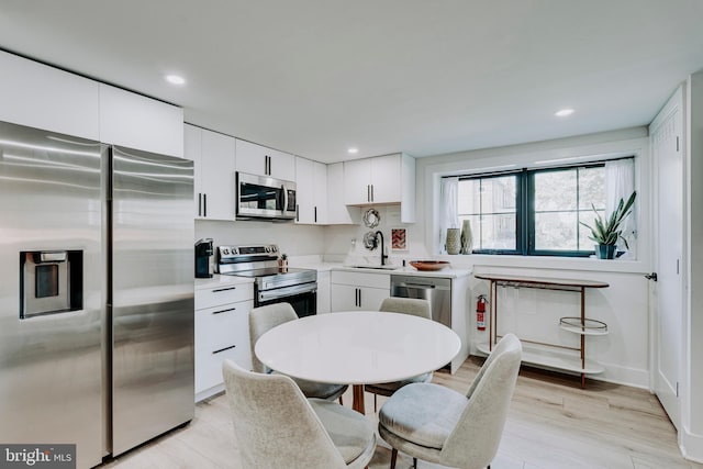 kitchen with appliances with stainless steel finishes, a sink, white cabinetry, light countertops, and recessed lighting