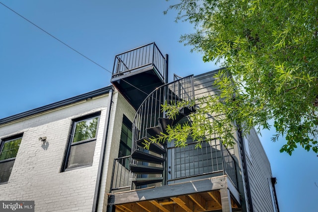 view of property exterior featuring stairs, brick siding, and a balcony