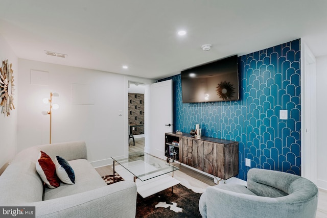 living room with wood finished floors, an accent wall, recessed lighting, and baseboards