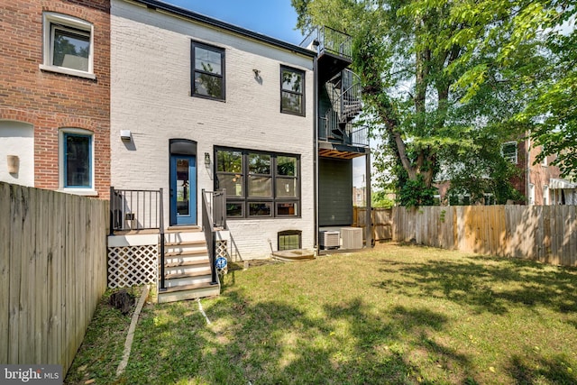 rear view of property featuring a balcony, brick siding, and central AC unit