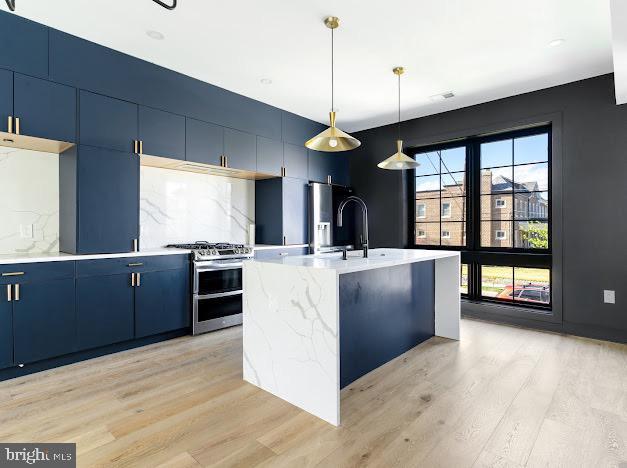 kitchen featuring range with two ovens, blue cabinetry, light wood-style floors, and tasteful backsplash