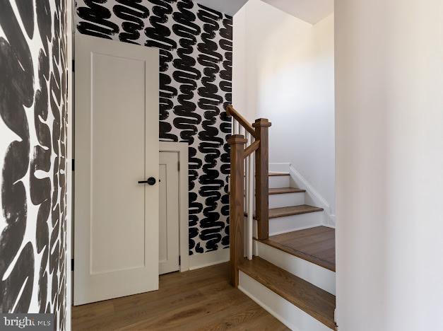 staircase featuring wood finished floors and baseboards