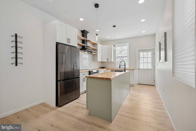 kitchen featuring stainless steel appliances, a kitchen island, white cabinets, wood counters, and pendant lighting