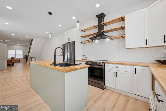 kitchen with butcher block countertops, stainless steel fridge, hanging light fixtures, white cabinets, and electric range