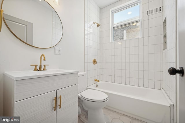 full bathroom with tile patterned flooring, vanity, tiled shower / bath combo, and toilet