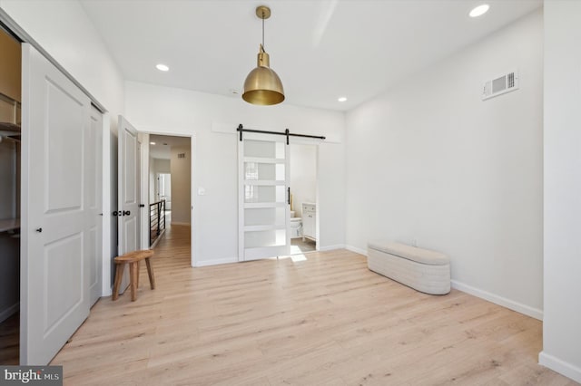 bedroom featuring a barn door and light hardwood / wood-style floors