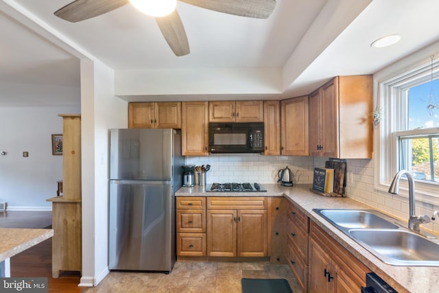 kitchen with tasteful backsplash, appliances with stainless steel finishes, sink, and ceiling fan