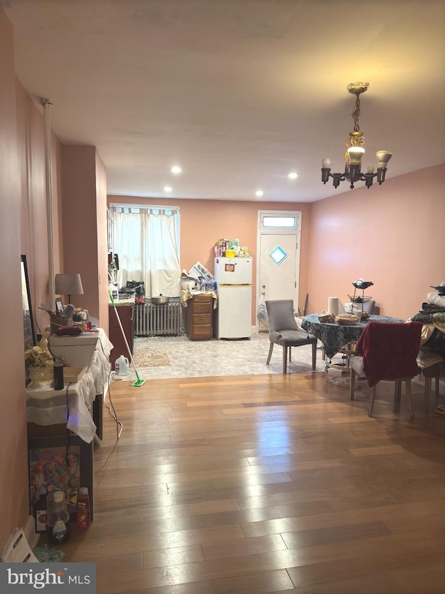 dining room featuring hardwood / wood-style floors, radiator heating unit, and a notable chandelier