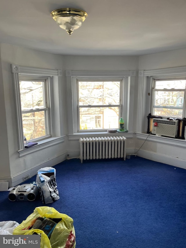 interior space with radiator heating unit, dark colored carpet, and cooling unit