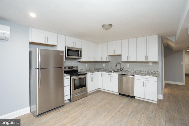 kitchen with light stone counters, stainless steel appliances, sink, light hardwood / wood-style floors, and white cabinets