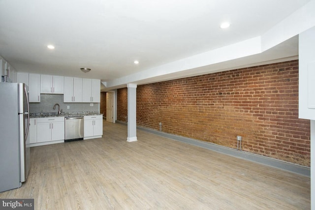 kitchen featuring white cabinets, sink, light stone countertops, light wood-type flooring, and appliances with stainless steel finishes