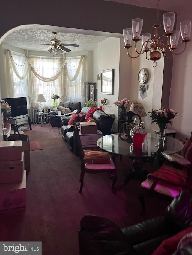 dining room with a textured ceiling, carpet floors, and ceiling fan with notable chandelier