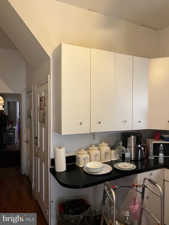 kitchen with white cabinetry, dark wood-type flooring, and lofted ceiling