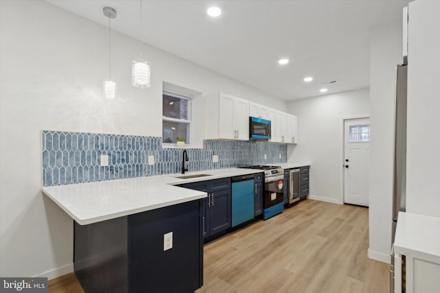 kitchen with pendant lighting, white cabinets, blue cabinets, sink, and kitchen peninsula