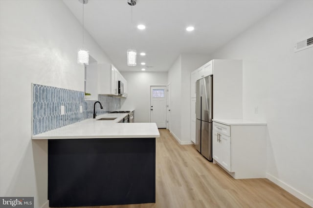 kitchen with white cabinets, stainless steel fridge, kitchen peninsula, and hanging light fixtures