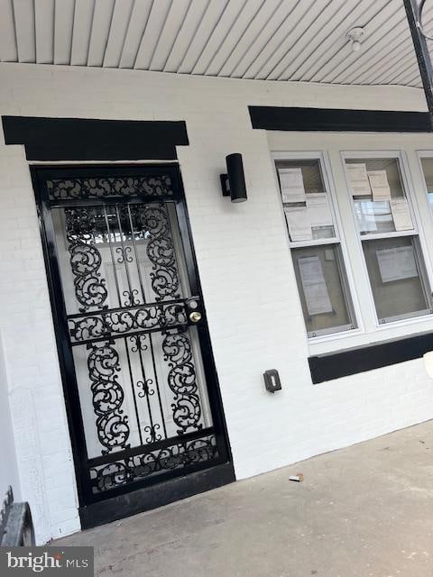 view of exterior entry with covered porch and brick siding