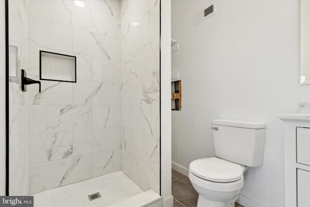 bathroom featuring tiled shower, vanity, toilet, and tile patterned flooring