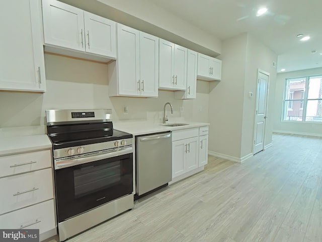 kitchen with white cabinets, stainless steel appliances, light hardwood / wood-style floors, and sink