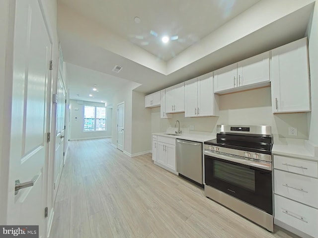 kitchen with white cabinetry, sink, stainless steel appliances, and light hardwood / wood-style flooring