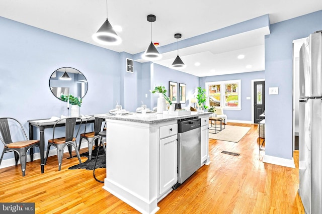 kitchen with light stone counters, stainless steel appliances, light hardwood / wood-style floors, white cabinetry, and hanging light fixtures