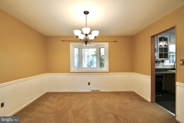 unfurnished dining area featuring a chandelier, sink, and carpet floors