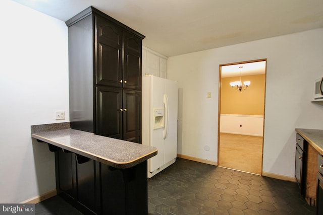 kitchen featuring kitchen peninsula, a kitchen breakfast bar, white fridge with ice dispenser, hanging light fixtures, and a chandelier