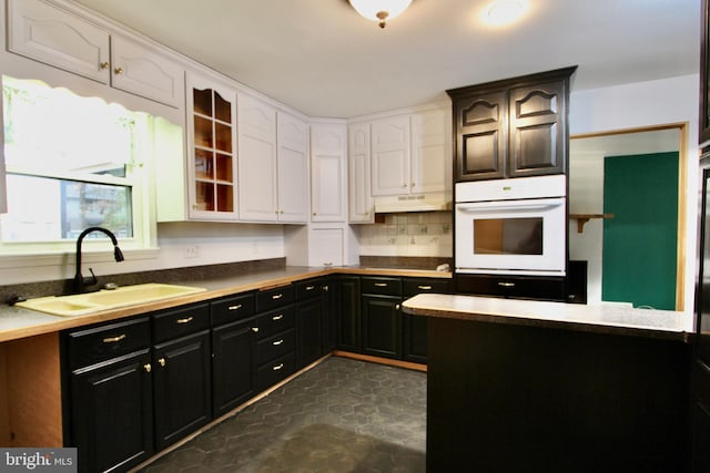 kitchen with white cabinetry, sink, tasteful backsplash, and white oven