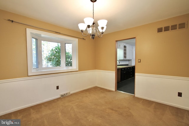 unfurnished room with sink, an inviting chandelier, and carpet floors