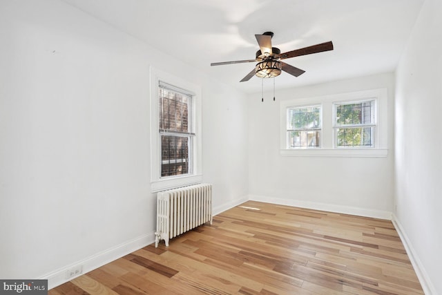 unfurnished room featuring radiator heating unit, light hardwood / wood-style flooring, and ceiling fan