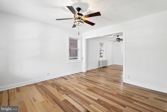 unfurnished living room featuring radiator, ceiling fan, light hardwood / wood-style floors, and a textured ceiling