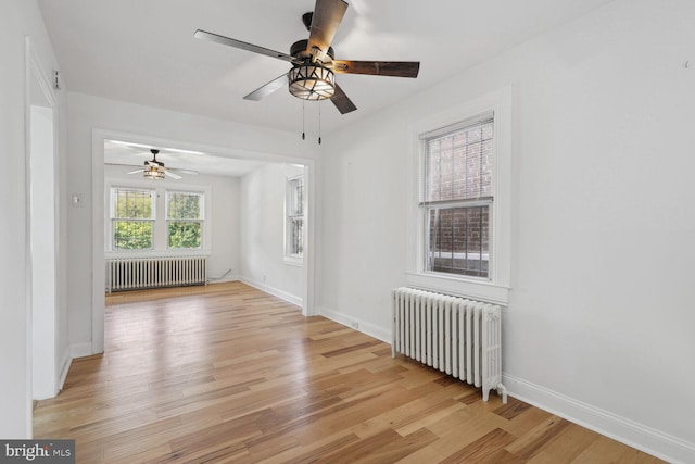 unfurnished room with radiator, ceiling fan, and light hardwood / wood-style floors