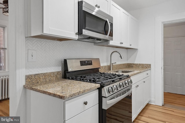 kitchen featuring white cabinets, sink, stainless steel appliances, and light hardwood / wood-style flooring