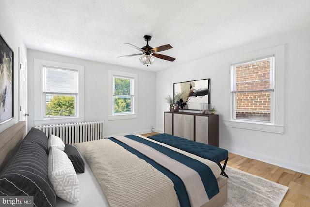 bedroom featuring radiator heating unit, hardwood / wood-style flooring, and ceiling fan