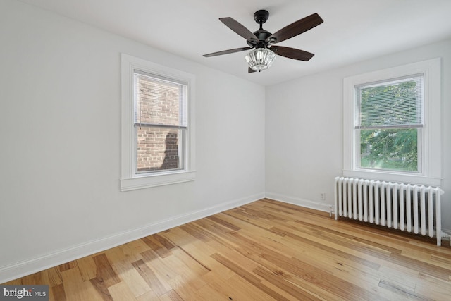 unfurnished room with light hardwood / wood-style floors, radiator, a healthy amount of sunlight, and ceiling fan