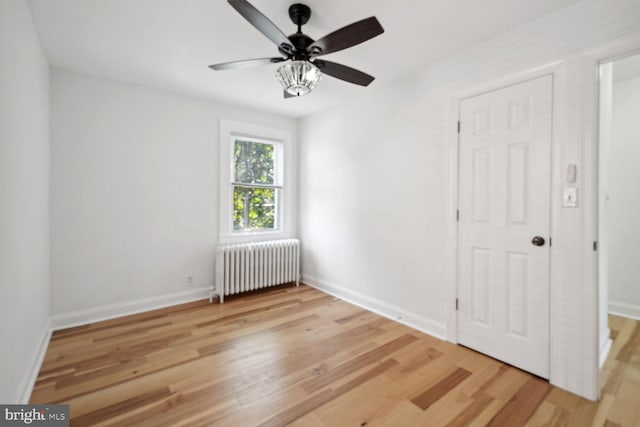 empty room with ceiling fan, light hardwood / wood-style floors, and radiator