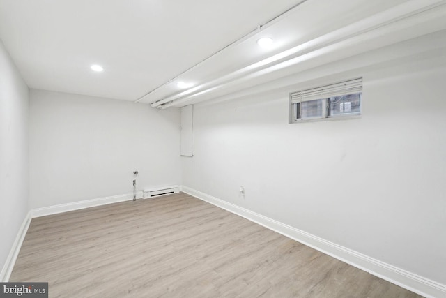 basement with light hardwood / wood-style flooring and a baseboard radiator