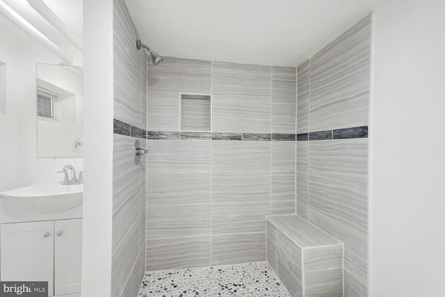 bathroom with a tile shower and vanity