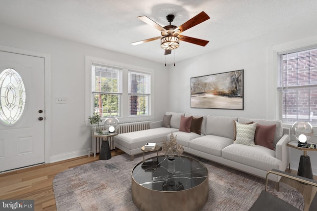 living room with ceiling fan, hardwood / wood-style floors, a textured ceiling, and radiator heating unit