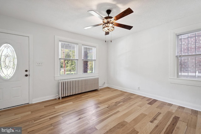 foyer with radiator heating unit, light wood-type flooring, a textured ceiling, and ceiling fan