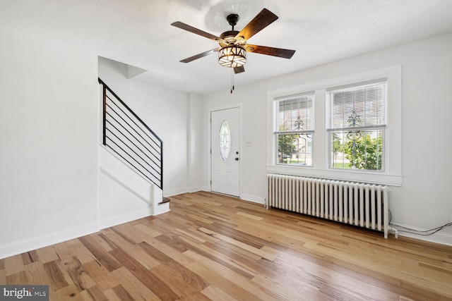 entryway with radiator, ceiling fan, light hardwood / wood-style floors, and a textured ceiling