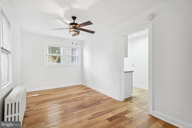 unfurnished room with radiator, ceiling fan, and light wood-type flooring