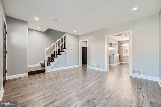 unfurnished living room featuring hardwood / wood-style flooring and an inviting chandelier