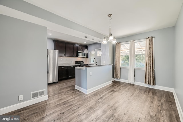 kitchen featuring stainless steel appliances, dark brown cabinetry, tasteful backsplash, decorative light fixtures, and hardwood / wood-style floors