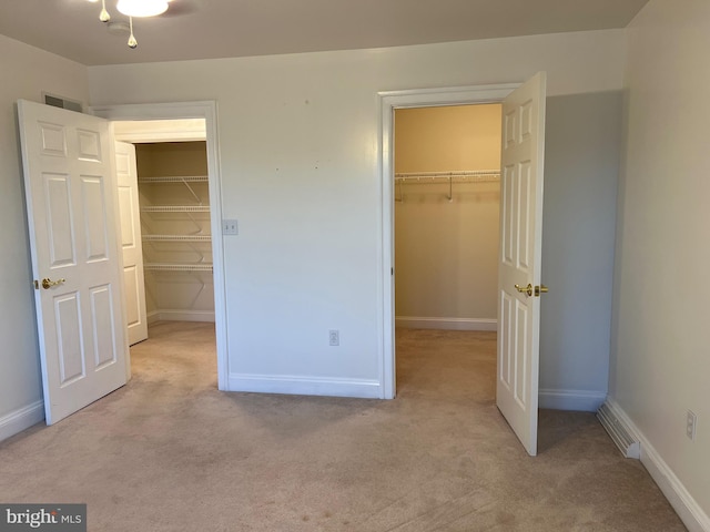 unfurnished bedroom featuring light carpet and a walk in closet